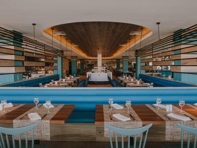 Restaurant moderne avec bancs bleus, tables en bois et éclairage élégant.