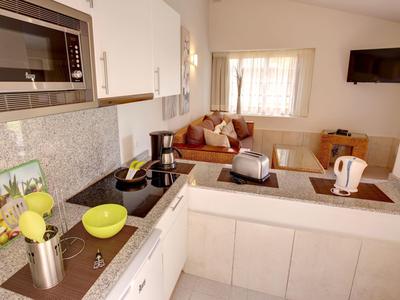 Cuisine moderne avec armoires blanches, bols verts et coin salon avec canapé en arrière-plan