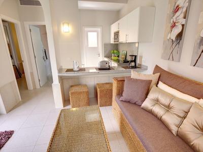 Salon confortable avec canapé, coussins, table et petit coin repas dans un appartement lumineux.