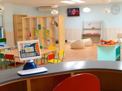Salle de jeux lumineuse et moderne pour enfants avec mobilier coloré et poufs confortables dans un hôtel.