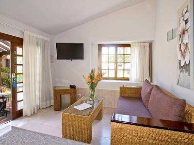 Coin chambre d'hôtel confortable avec canapé, fenêtre, télévision et accès à la terrasse.