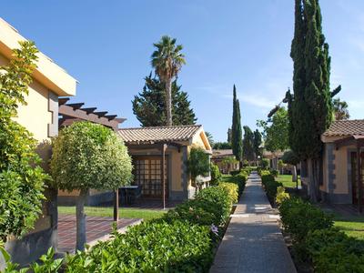 Allée entre de petites maisons bien entretenues et des jardins sous un ciel bleu