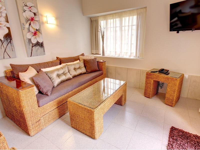 Coin salon confortable avec meubles en rotin, table basse en verre et art mural décoratif.