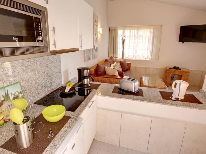 Cuisine moderne avec armoires blanches, bols verts et coin salon avec canapé en arrière-plan