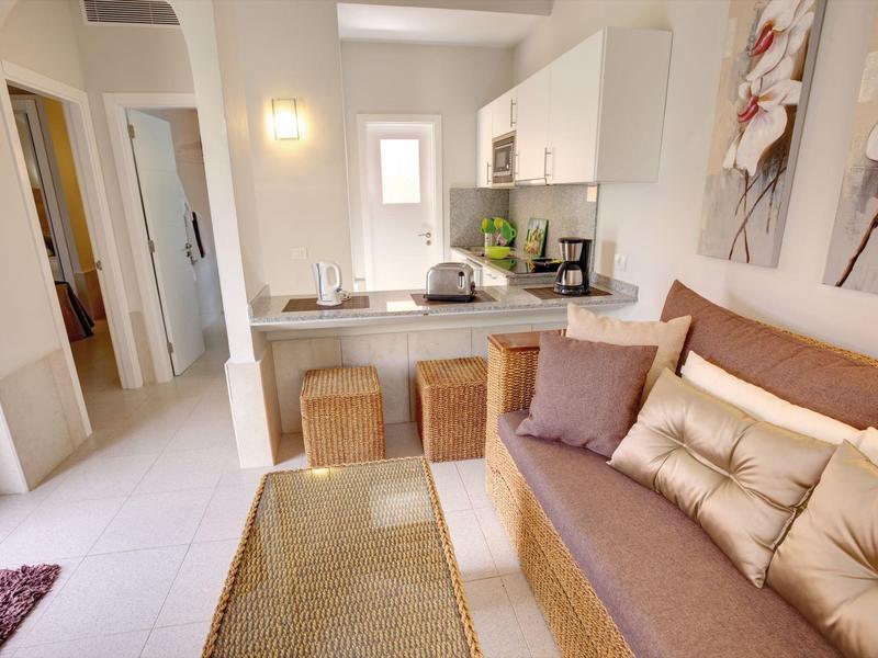 Salon confortable avec canapé, coussins, table et petit coin repas dans un appartement lumineux.