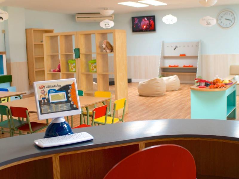 Salle de jeux lumineuse et moderne pour enfants avec mobilier coloré et poufs confortables dans un hôtel.