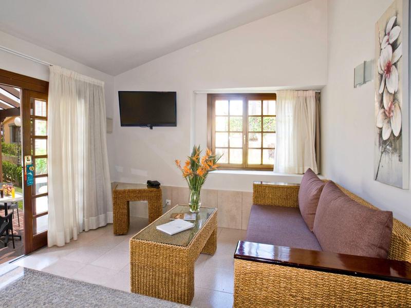 Coin chambre d'hôtel confortable avec canapé, fenêtre, télévision et accès à la terrasse.