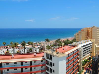 Vista de una ciudad costera con hoteles y mar azul bajo un cielo despejado.