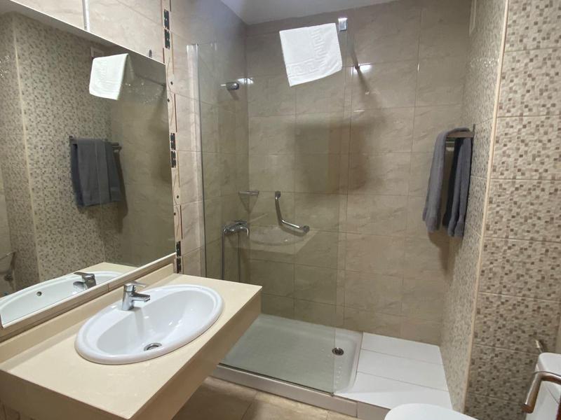 Baño moderno con lavabo, ducha e inodoro en tonos neutros.