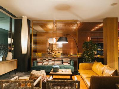 Gemütliches Wohnzimmer mit braunen Ledersofas, Holzmöbeln, Hänge- und Stehlampen bei Abendlicht.