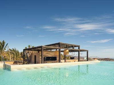 Pavillon moderne au bord d'une piscine bleue claire sous un ciel bleu avec des palmiers en arrière-plan.
