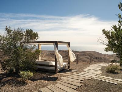Chaises longues dans un paysage désertique avec chemin en bois et ciel clair.