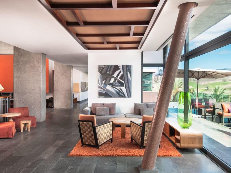 Moderner Wohnraum mit orangefarbenen Sesseln, großen Fenstern und Holzdeckendetails.