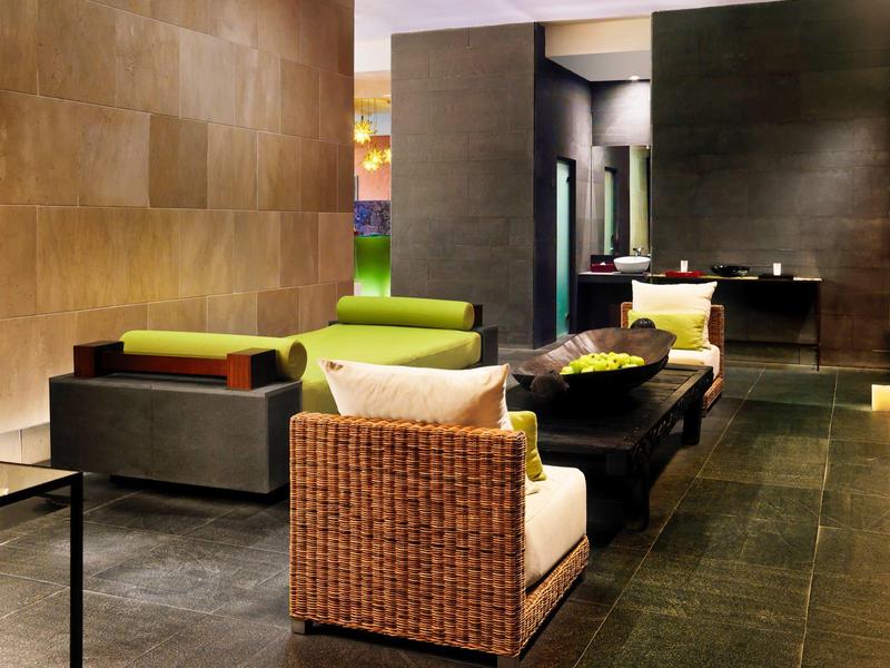 Moderner Wohnraum mit braunen Wänden, großer Couch, Korbsessel und schwarzem Couchtisch.