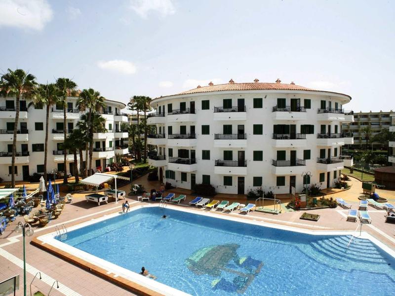 Mehrstöckige Wohngebäude umgeben großen rechteckigen Pool mit Wasserspiel im Freien.