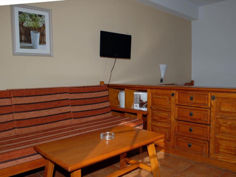 Woonruimte met gestreepte bank, houten tafel, ladekast en wanddecoratie in een hotelkamer.