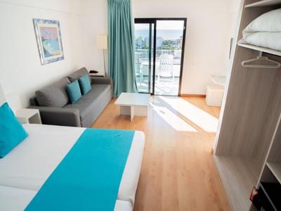Helles Hotelzimmer mit Doppelbett, Sofa, Balkon und modernem Möbelstil.