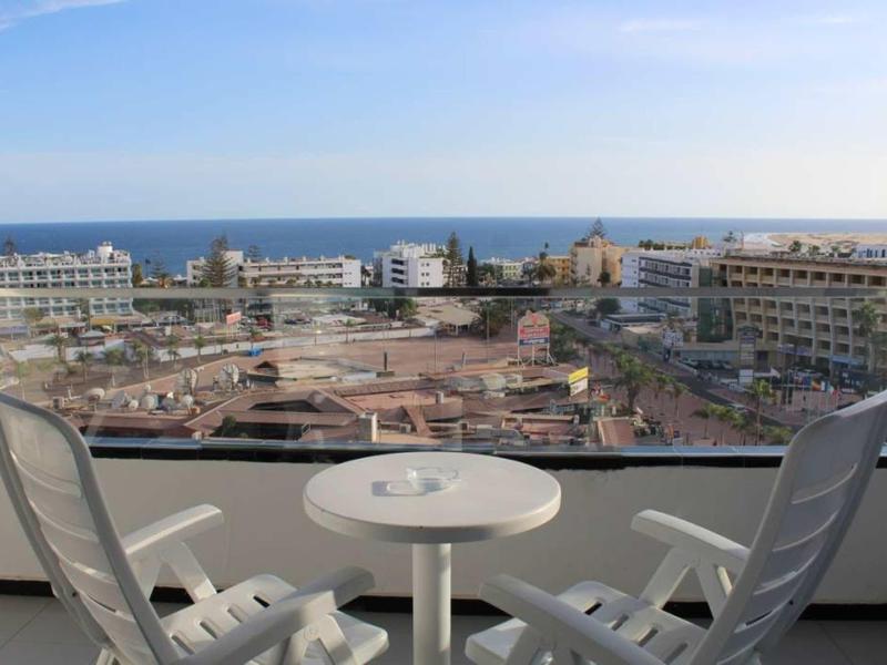 View from balcony with two chairs and table overlooking hotel and sea in the background.