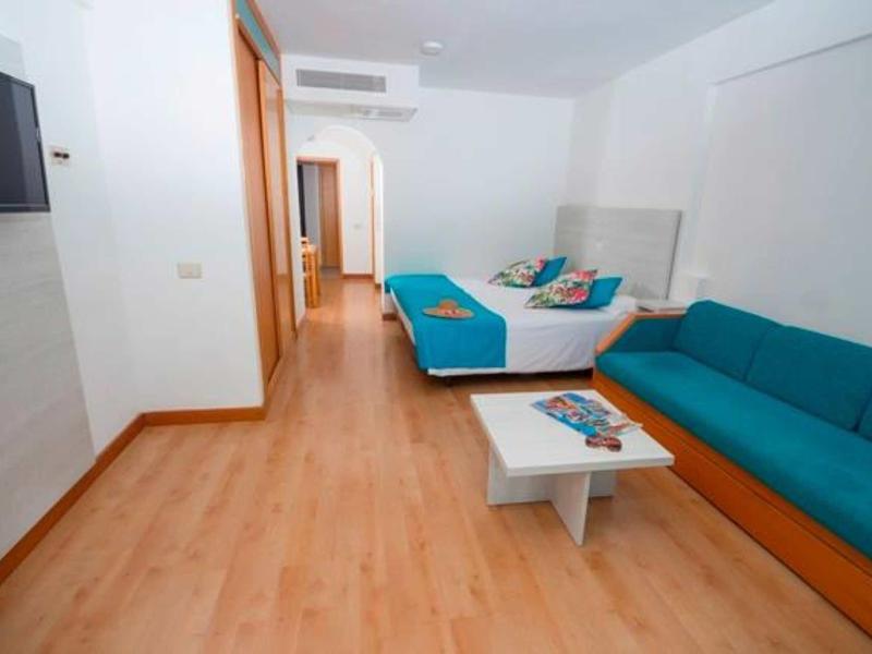 Modern hotel room with double bed, sofa, and flat-screen TV