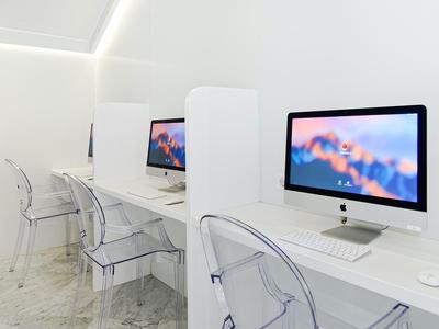 Nowoczesne miejsce pracy z białymi biurkami i przezroczystymi krzesłami w jasnym pokoju.