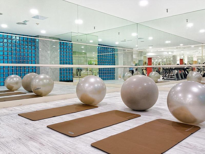 Moderner Fitnessraum mit Matten, großen Gymnastikbällen und Spiegelwand mit heller Beleuchtung.