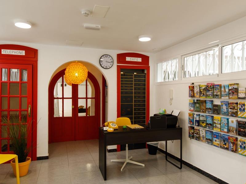 Innenraum einer Touristeninformation mit rotem Telefonhäuschen, Prospektwand und schwarzem Empfangstisch.