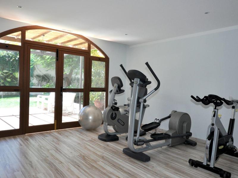 Lichte fitnessruimte met grote ramen en diverse fitnessapparatuur.