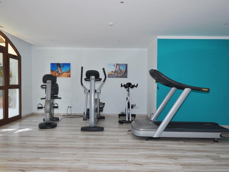 Interieur van een fitnessruimte met een loopband, hometrainer en gewichten.