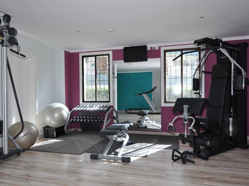 Moderne fitnessruimte met trainingsapparatuur, spiegels en grote ramen in een hotel.