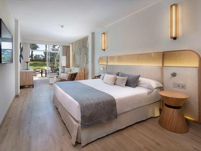 Moderní hotelový pokoj s manželskou postelí, posezením a výhledem na zahradu