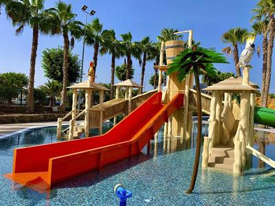 Vodní park s barevnými skluzavkami a palmami v hotelovém bazénu.