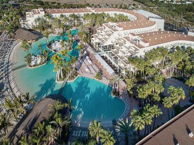 Letecký pohled na resort s velkým bazénem, lagunou a palmami.