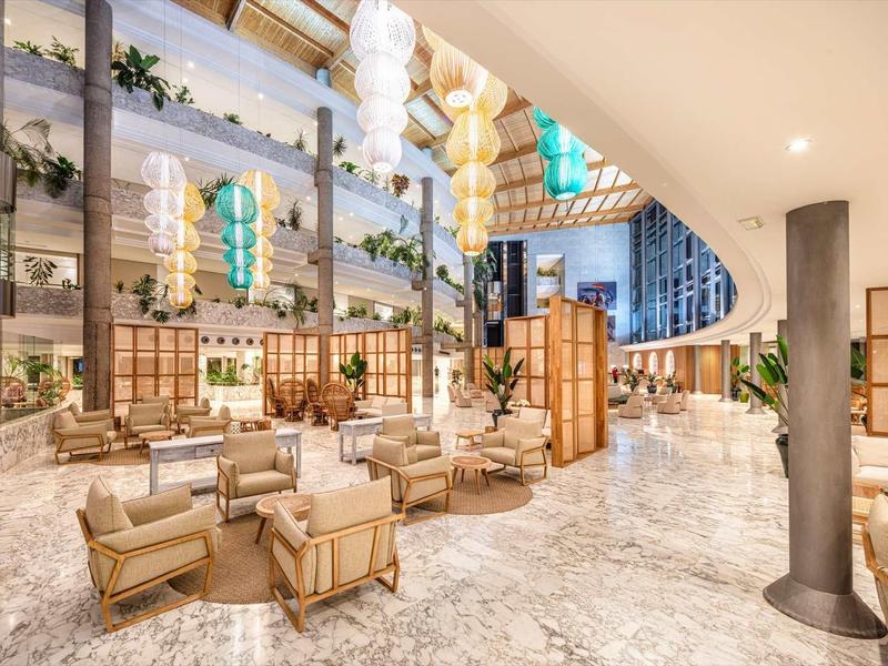 Světle hotelové lobby s moderním nábytkem a velkými okny na světlé mramorové podlaze