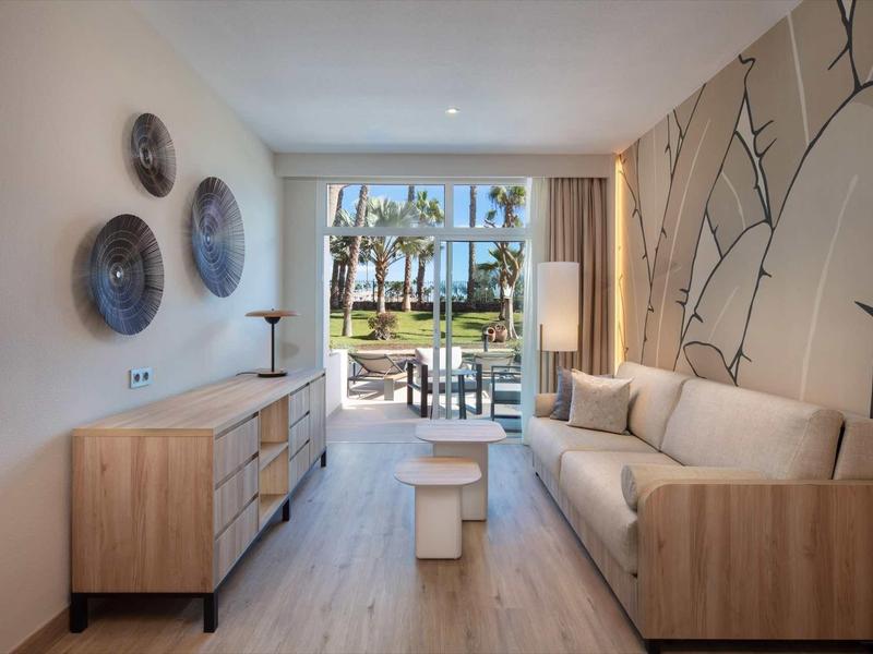 Moderní obývací pokoj s pohovkou, komodou a výhledem na terasu a zahradu.