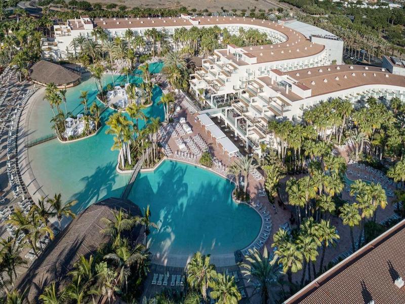 Letecký pohled na resort s velkým bazénem, lagunou a palmami.