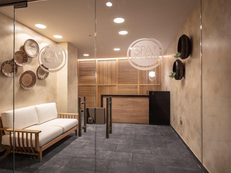 Moderní hotelová lobby se dřevěnými stěnami, pohovkou, kulatými dekoracemi a recepčním pultem.