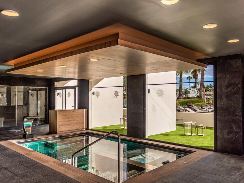 Moderní vnitřní bazén s velkým oknem a dřevěným stropem v hotelu