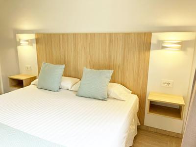Modernes Hotelzimmer mit einem großen Bett, Holzpaneel und zwei Nachttischen mit Lampen.