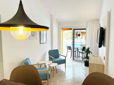 Modern eingerichtetes Wohnzimmer mit blauen Sesseln und Zugang zum Balkon mit Blick auf den Pool.