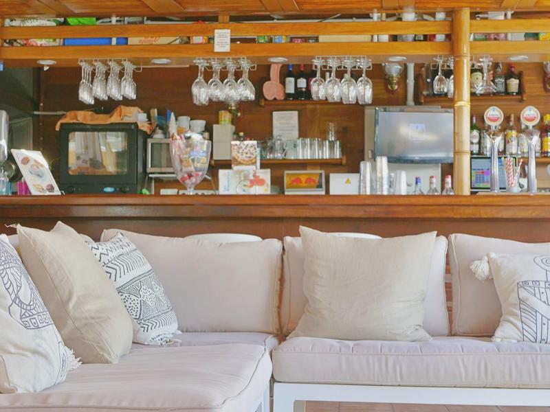 Salon confortable avec canapés blancs et comptoir de bar en bois en arrière-plan.