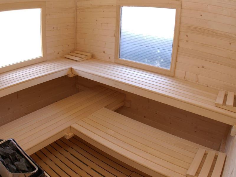 Sauna lumineuse avec bancs en bois et deux fenêtres laissant entrer la lumière du jour