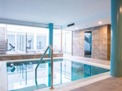 Moderne binnenzwembad met glazen wanden en zuilen, lichte en rustige sfeer.