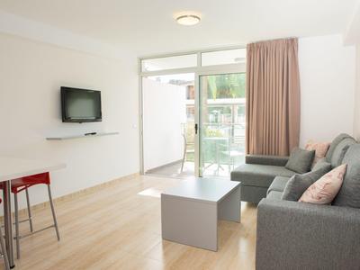 Modern woonkamer met grijze bank, aan de muur gemonteerde tv en toegang tot balkon.