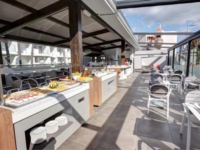 Modern hotel dakterras buffet met zitgedeelten onder een blauwe lucht.