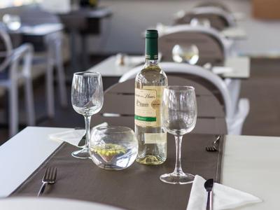 Witte wijnfles en twee wijnglazen op een gedekte tafel in een lichte restaurant.