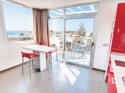 Lichte moderne kamer met groot raam, kleine tafel en uitzicht op terras en zee.