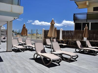 Lege ligstoelen met parasols op een hotelterras onder een zonnige lucht.