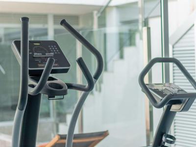 Équipements de fitness dans une pièce lumineuse avec de grandes fenêtres et une décoration moderne.