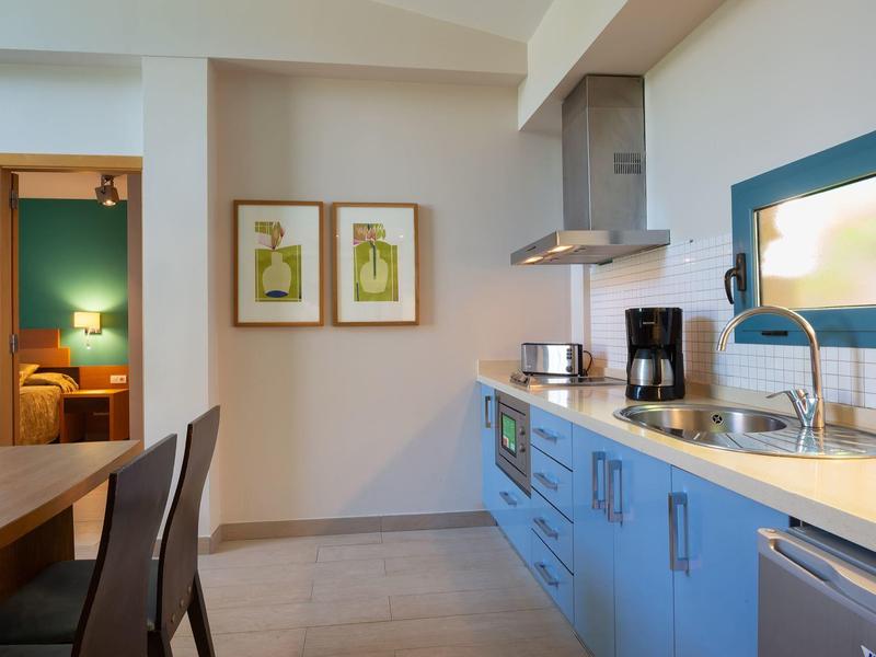 Modern kitchen with blue cabinets, wooden dining table, chairs, and framed wall art.