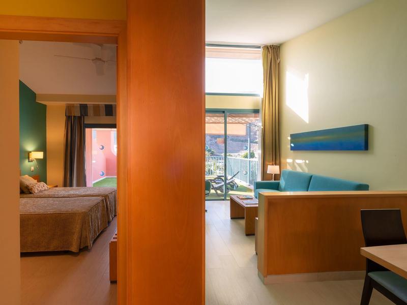 Hotel room with bed area separated by wooden partition and balcony with mountain view
